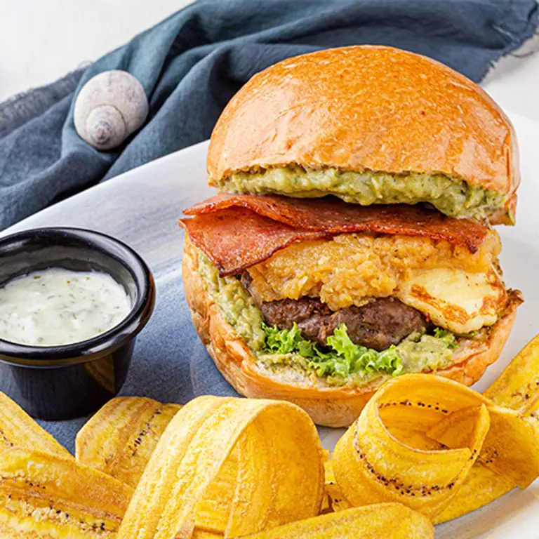 Burger Bay con tocineta, guacamole y queso asado, con tostones