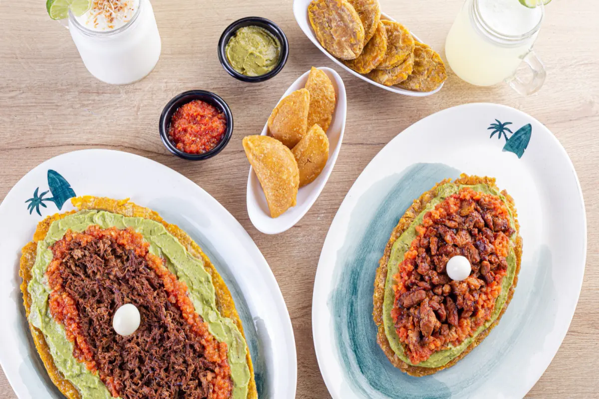 Mesa con patacones cargados, guacamole, hogao y salsas de Patacón Bay