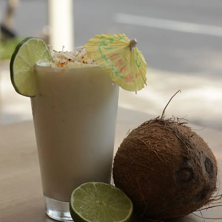 Limonada de coco con limón y un coco al lado