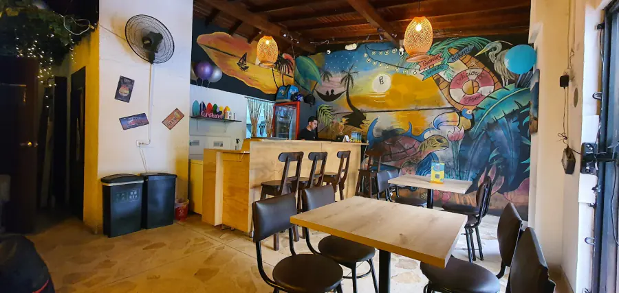 Interior de Patacón Bay con mural playero, barra y mesas altas