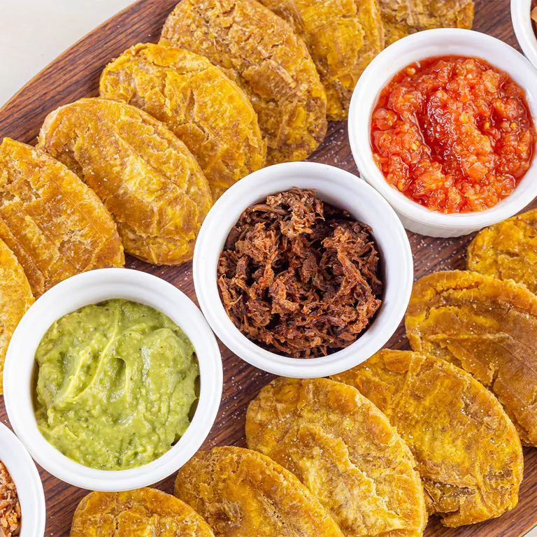 Tabla de pataconcitos con hogao, guacamole y proteínas para compartir