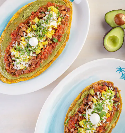 Dos patacones servidos con aguacate y salsas